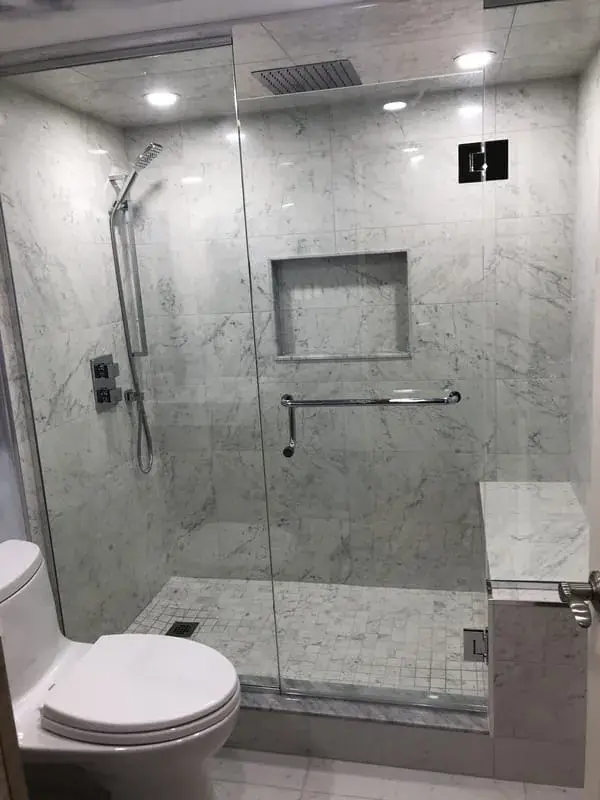 Marble look walk in shower with a glass panel and a rain head