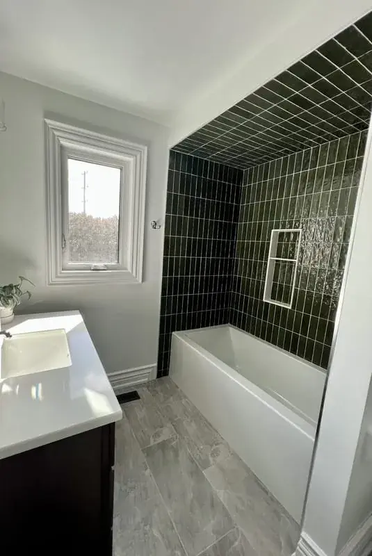 Bathtub with a dark green vertical tile surround