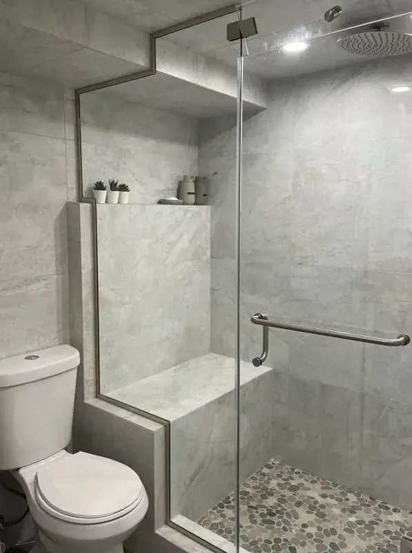 Grey tile walk-in shower with a pebble floor and a built-in bench