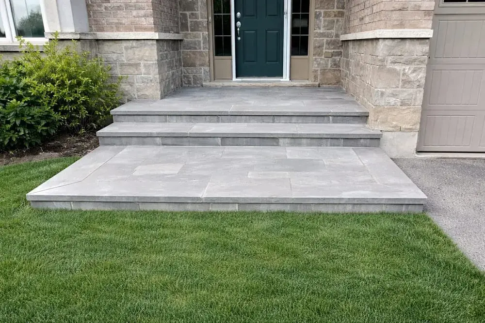 Wide grey stone steps leading up to a teal front door