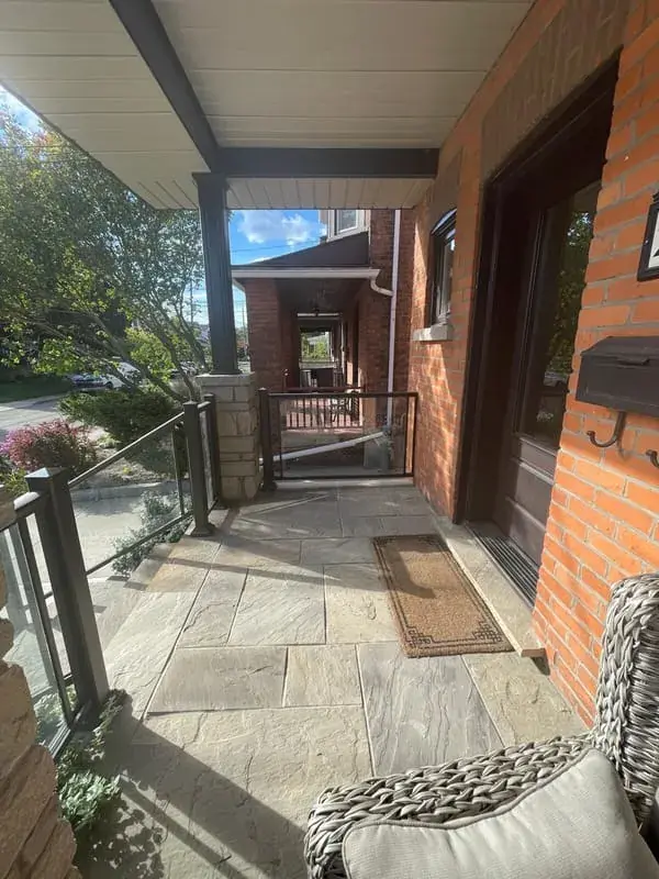 Under a covered porch: flagstone floor with a glass and bronze railing