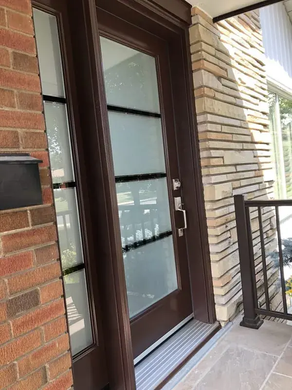 A dark entry door with glass panels set in a brick and stone surround