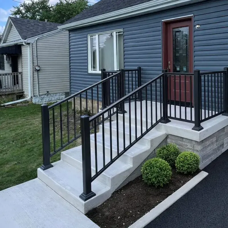 Concrete stairs with a black aluminum railing on a blue sided house