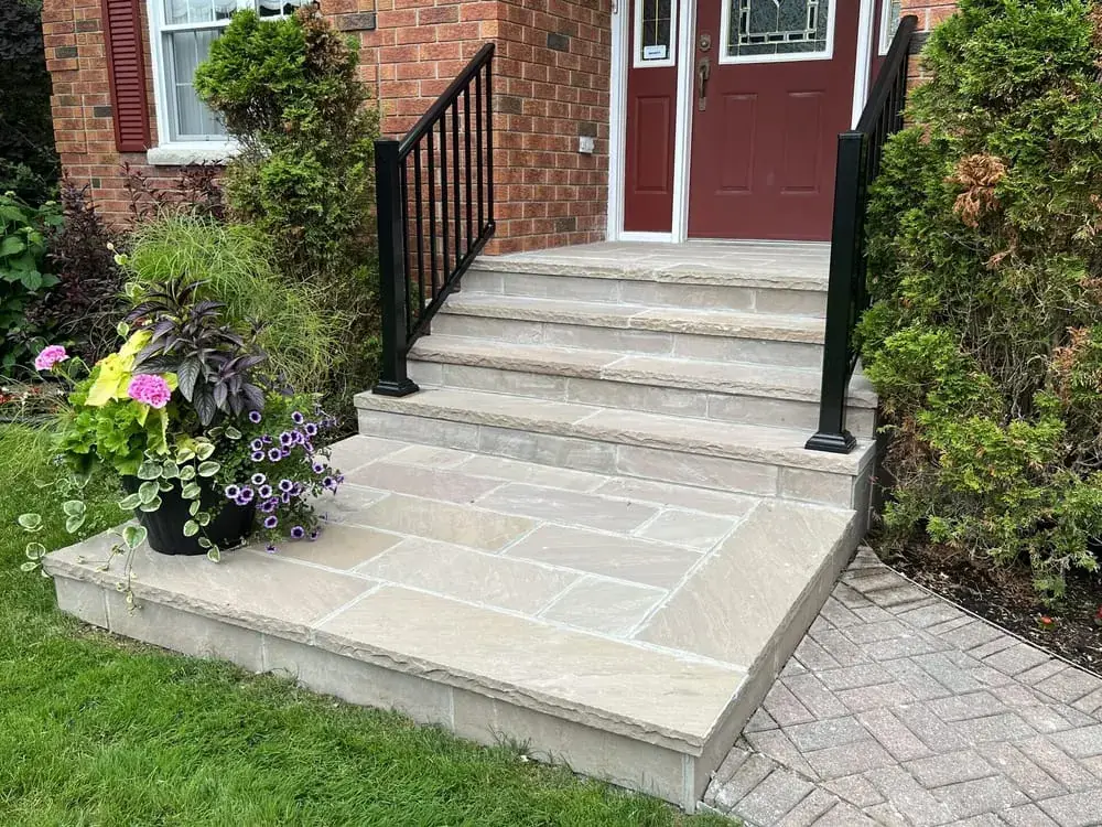 Flagstone steps and landing up to a red door, with black railings and flowers