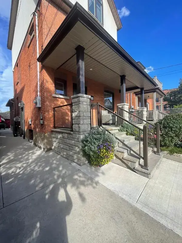 Stone column porch with a bronze railing and flagstone steps