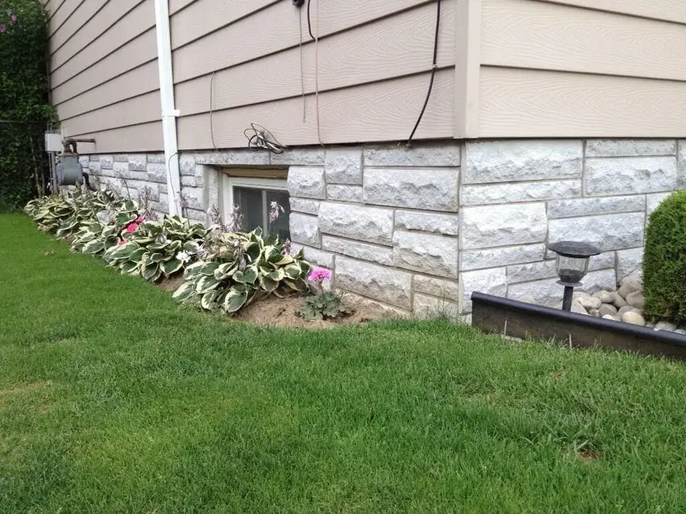 Natural stone veneer along the base of a house wall, below the siding