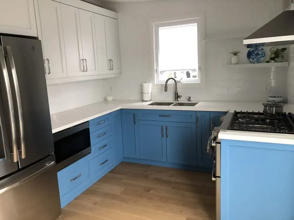 U-shaped kitchen with blue lower cabinets, white uppers and stainless appliances
