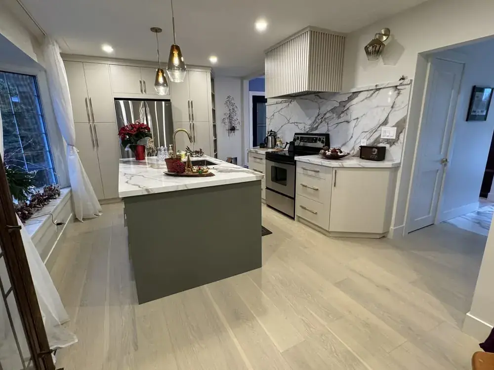 Kitchen with a green-grey island, a marble slab backsplash and a pendant light