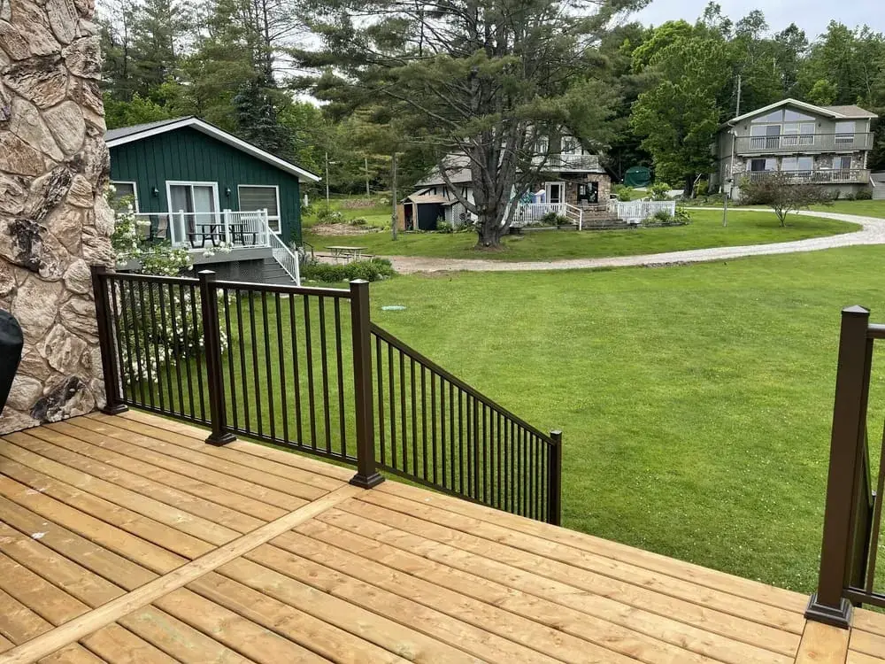New backyard deck with railings and a view past the yard